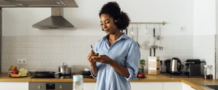 vrouw maakt een boodschappenlijstje in haar keuken